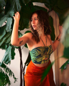girl in green top and orange skirt around plants